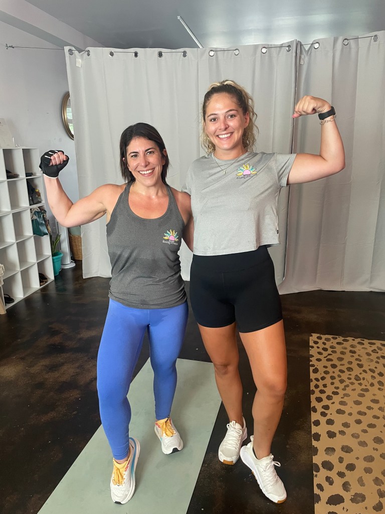 Two women flexing their bicep muscles.